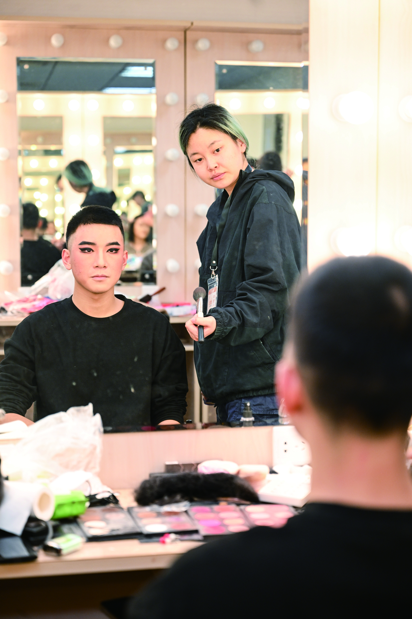 演员们在化妆师的帮助下仔细地调整着妆容